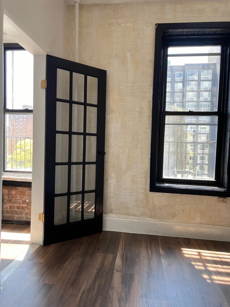 Manhattan bedroom with dark wood accents and a window