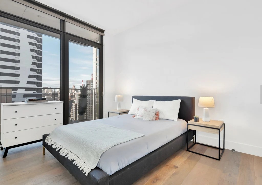 Modern bedroom with large windows in a Queens listing