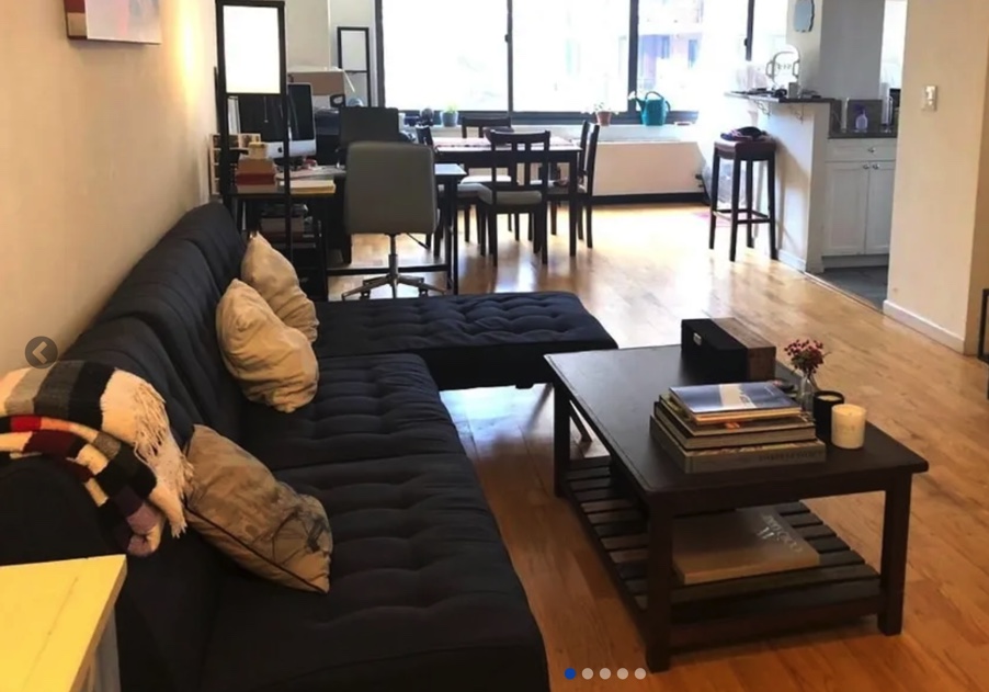 apartment photo of living room with couch, coffee table, and kitchen furniture in background